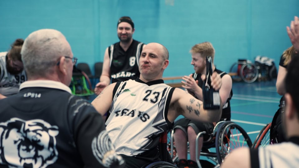 Famous wheelchair basketball team celebrating victory after game at sports hall.