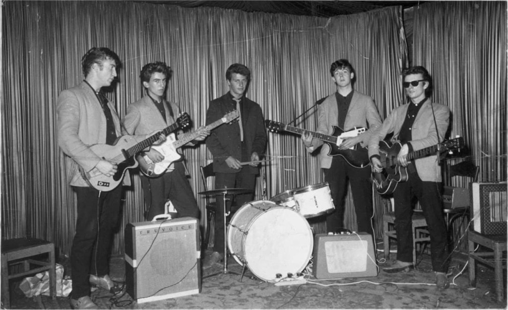 Vintage band performing with guitars and drums on stage, capturing classic music moments.