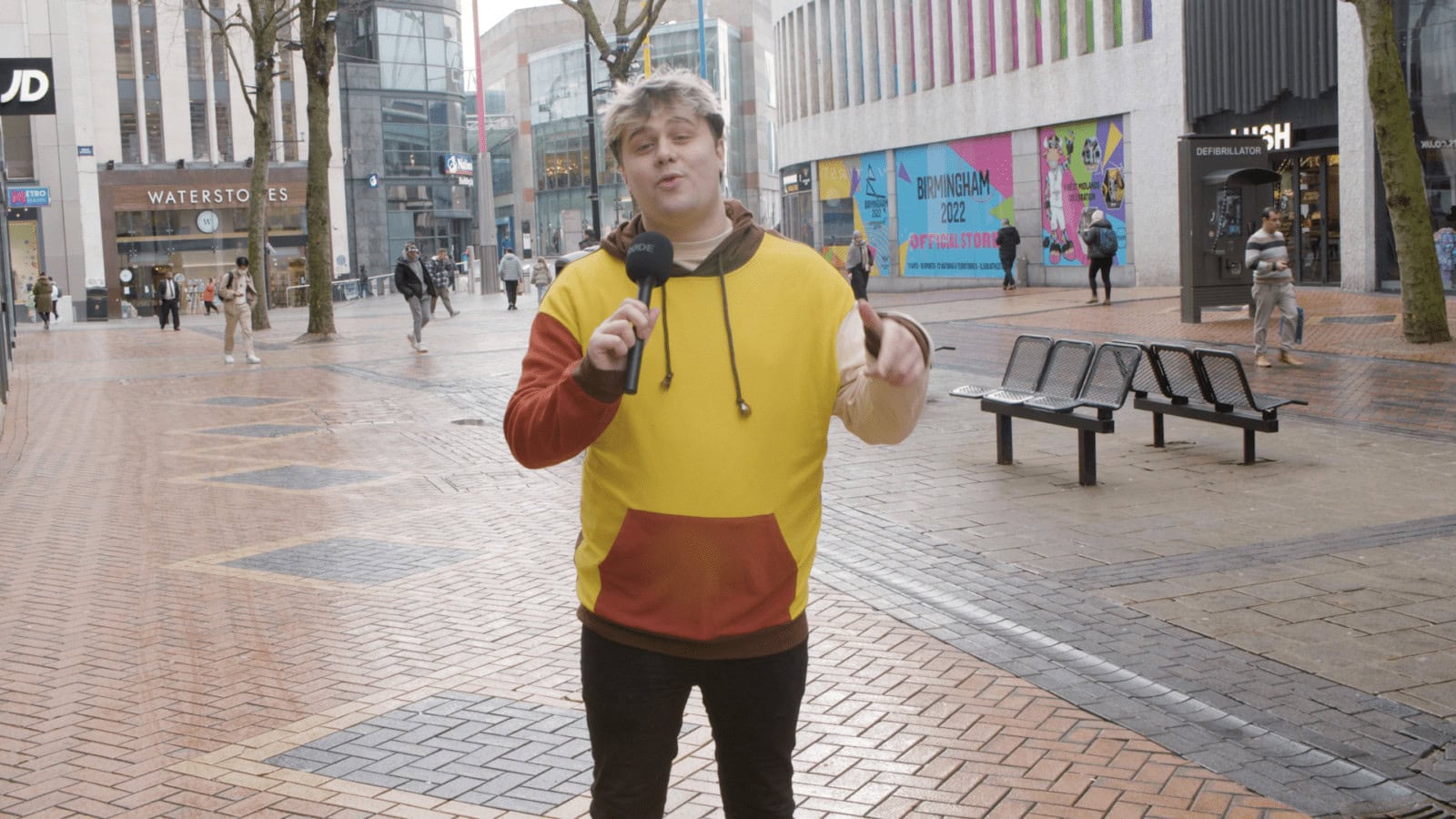 Vibrant young man filming a street interview in Birmingham city centre during daytime.