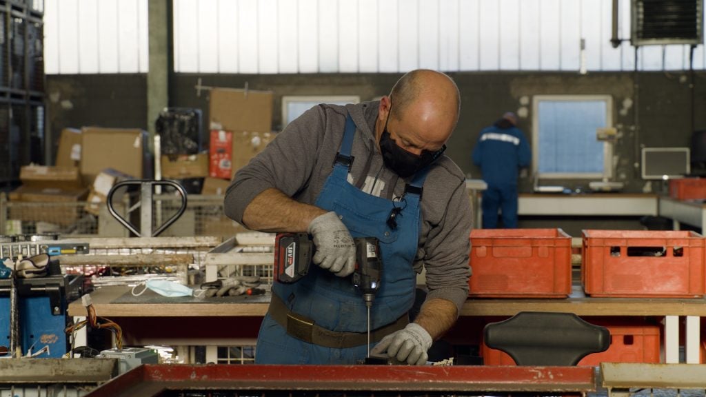 Industrial worker repairing electronic device in workshop. Audience Value.