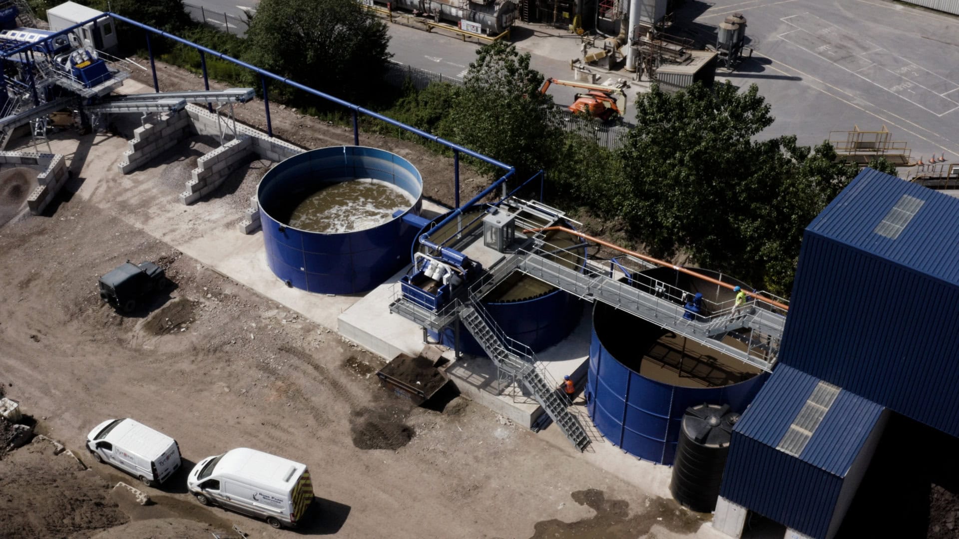 Clean water treatment facility with large blue tanks and processing equipment.