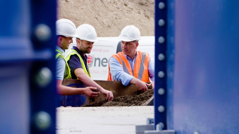 Construction workers at a building site discussing soil and foundation work.