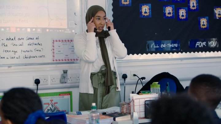Elderly woman teaching in classroom with whiteboard and students, education, classroom, teaching, learning, school, teacher in a school setting.