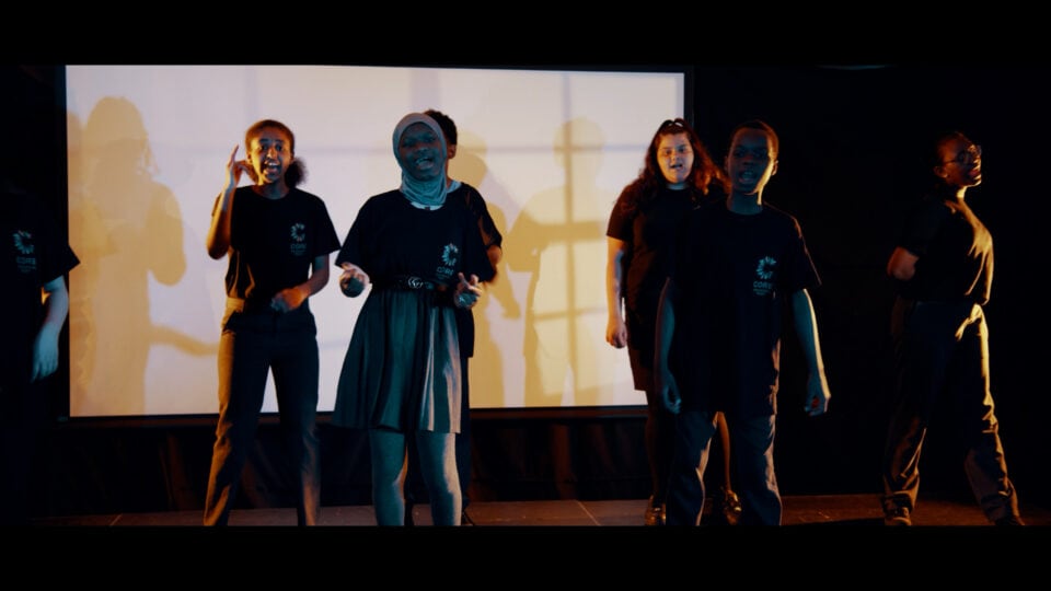 Diverse girls performing on stage in black T-shirts with 