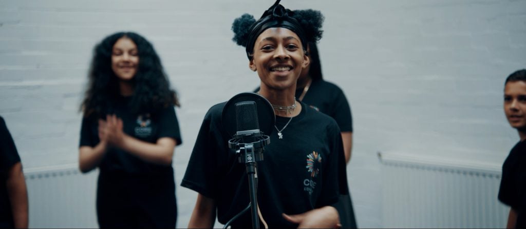 Diverse group of young people recording a video with a microphone in a studio setting.