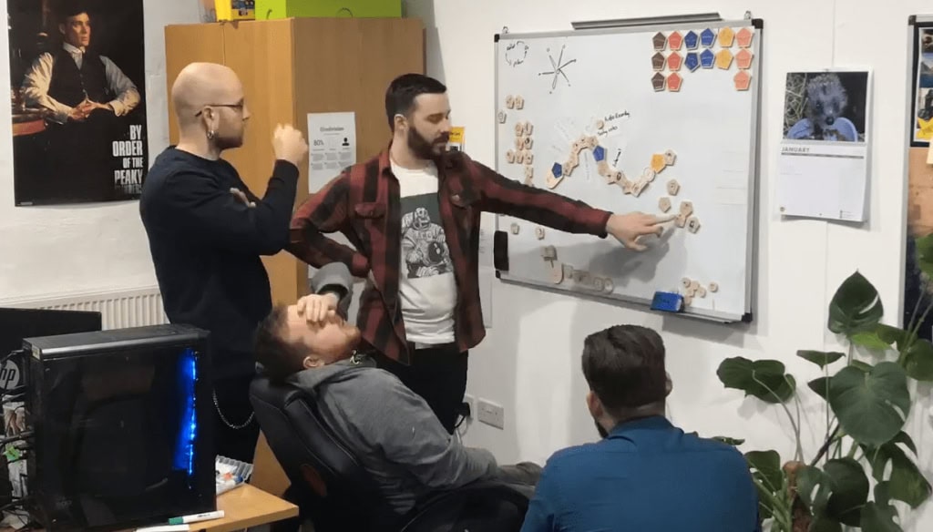 Creative team collaborating in an office with whiteboard and brainstorming ideas for film production.