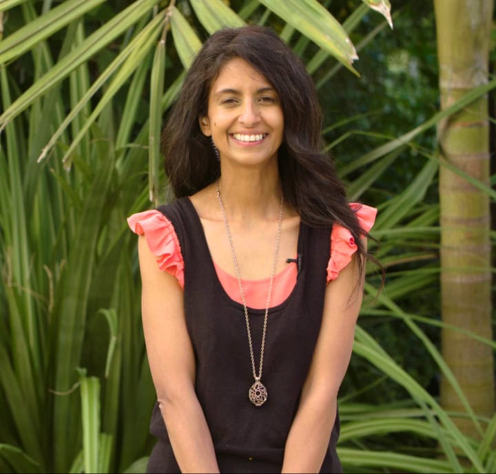 Vibrant woman smiling outdoors in tropical garden for Film Division promotional content.