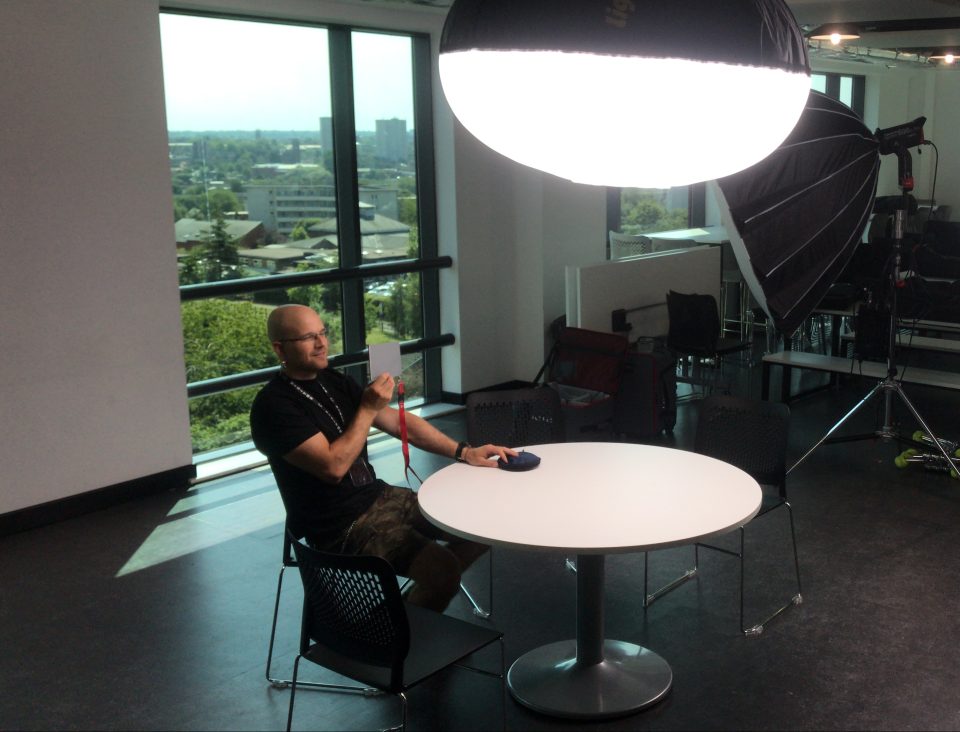 Close-up of a man sitting at a table during a professional video shoot in a modern studio.