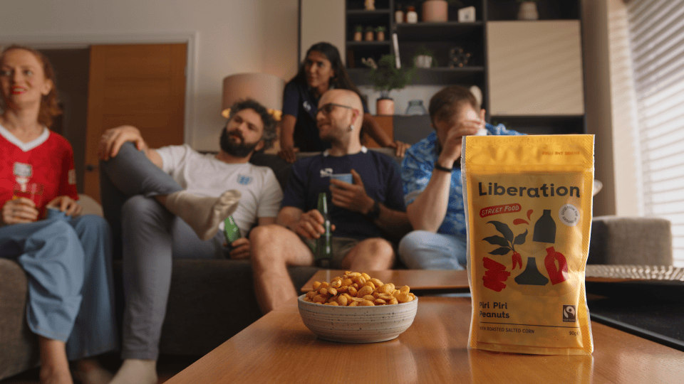 Baked peanuts on a table in front of a group of friends watching TV at home.