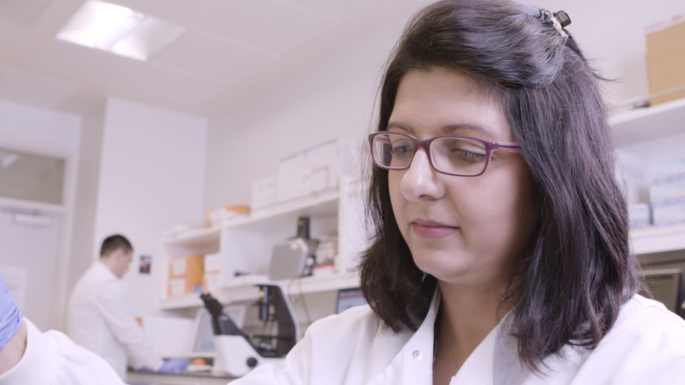 Microbiologist working in a laboratory with scientific equipment and research materials.
