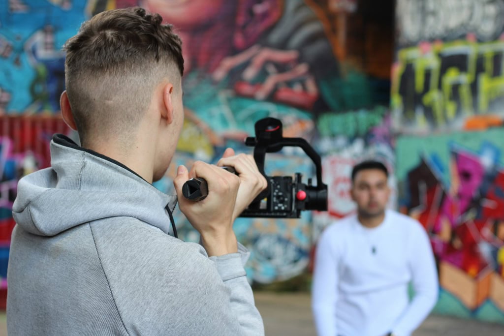 Professional videographer filming urban graffiti art for a documentary project.