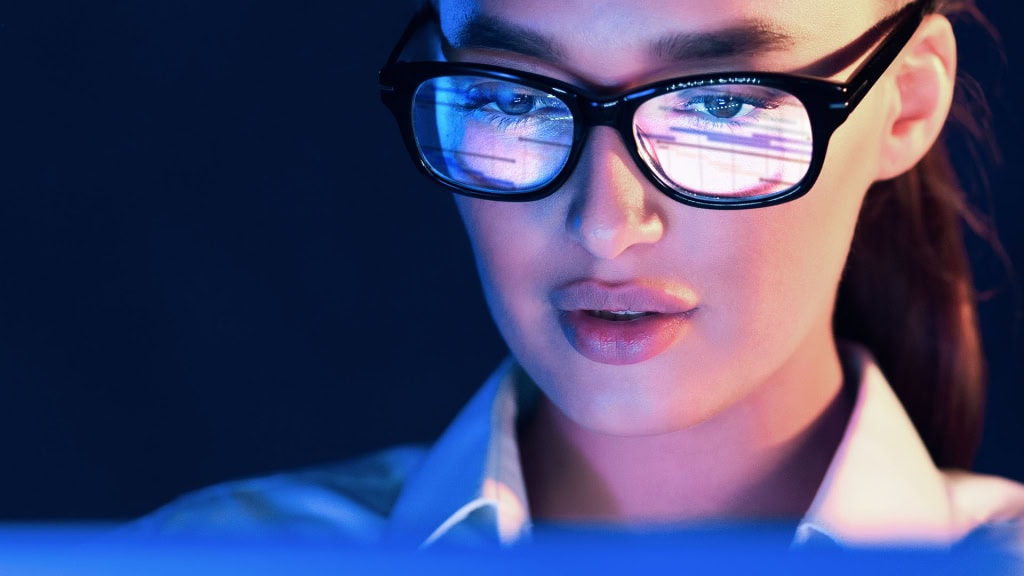 Futuristic woman wearing glasses with reflections of digital screens, emphasising technology and innovation.