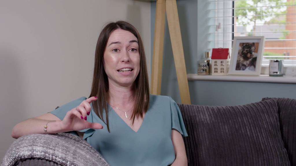 Professional woman speaking during video interviews or testimonial in a modern home setting.