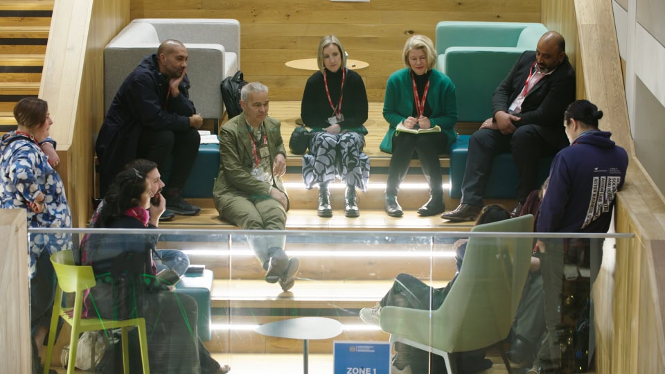 Meeting of diverse professionals discussing in modern office lounge area.