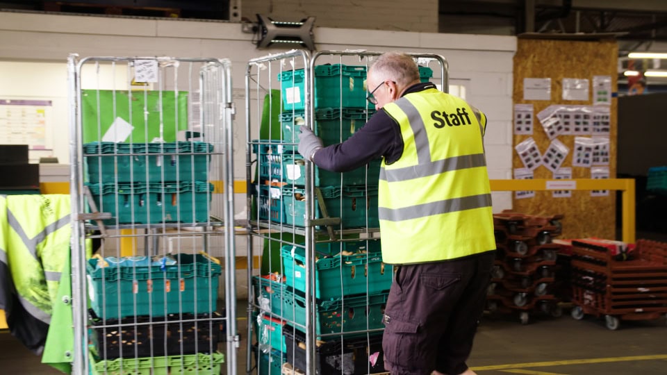 Loading cargo and supplies in a warehouse using carts, staff member organising items.