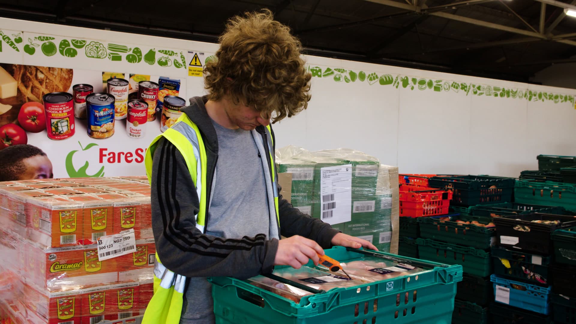 Can of canned food being inspected at the Food Bank warehouse in a charitable food distribution setting.