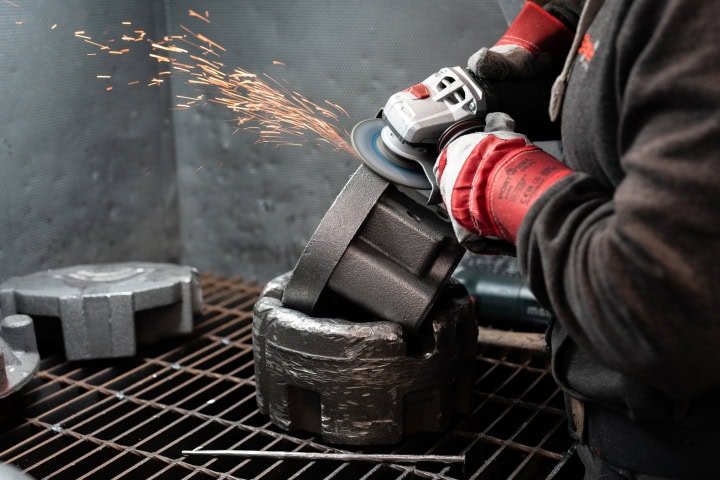 Worker grinding metal with an angle grinder, sparks flying in industrial setting. Manufacturing video production