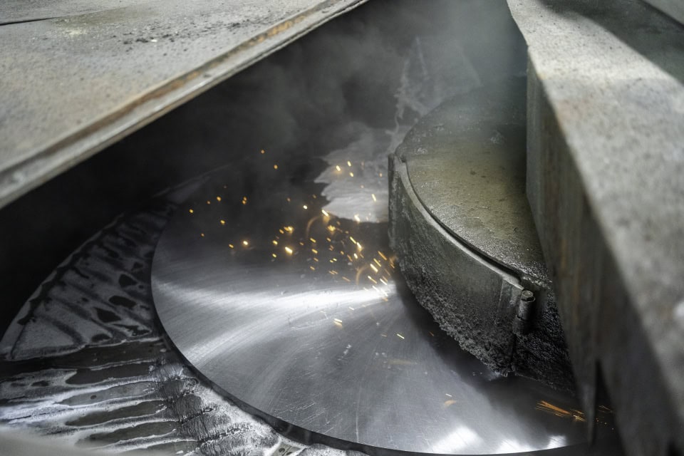 Industrial metal cutting process with sparks and machinery.