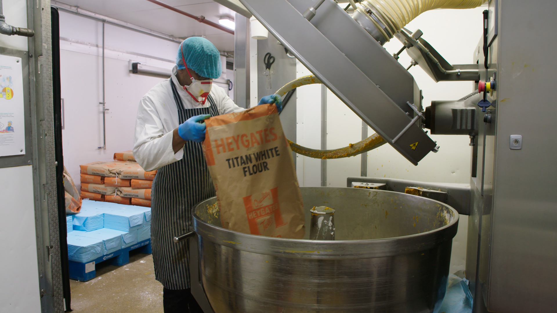 Worker operating industrial equipment in a food manufacturing facility.