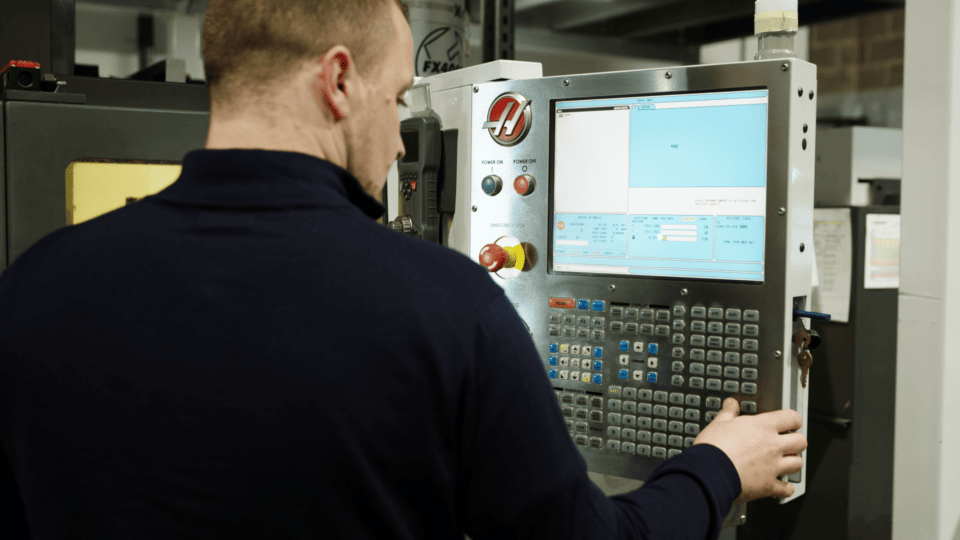 Man operating a CNC machine in a factory promoting sustainable manufacturing.