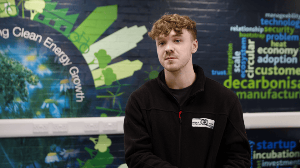 Young man in black jacket at eco-friendly energy event.